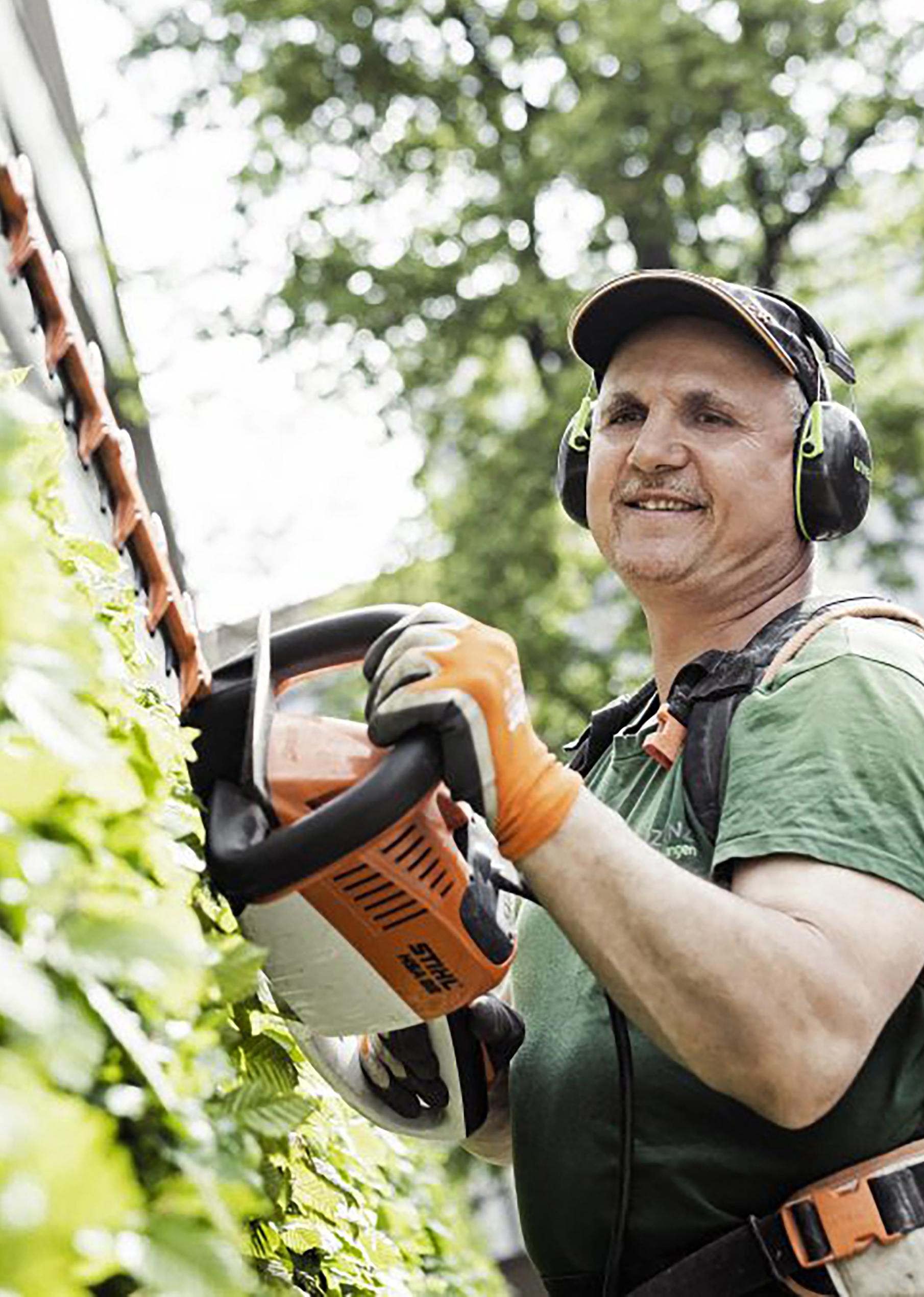 Mitarbeiter im Vinzenz-Garten- und Landschaftsbau mit elektrischer Heckenschere.