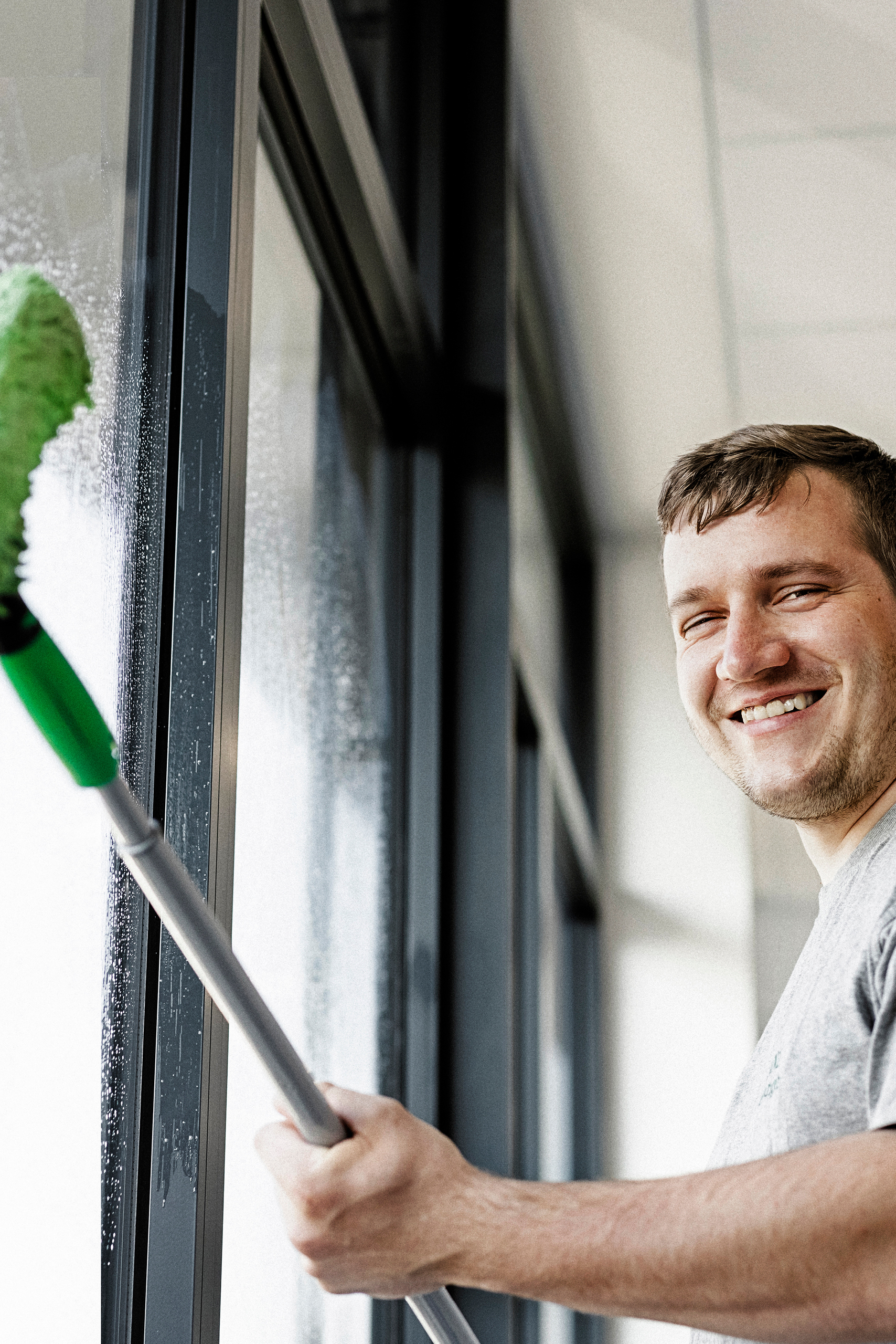 Mann beim Fensterputzen.