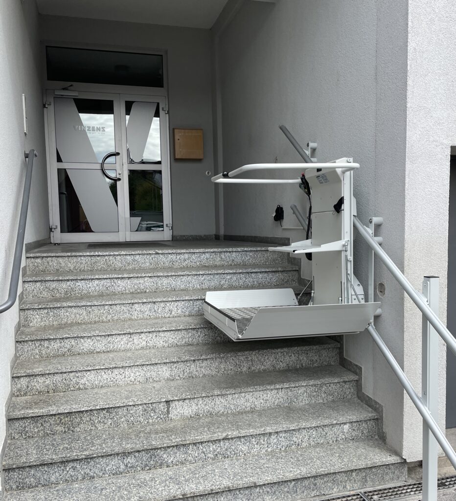 Auf dem Bild ist der Haupteingang von Vinzenz Würzburg zu sehen. An der Treppe befindet sich auf halber Höhe der neue Treppenlift.