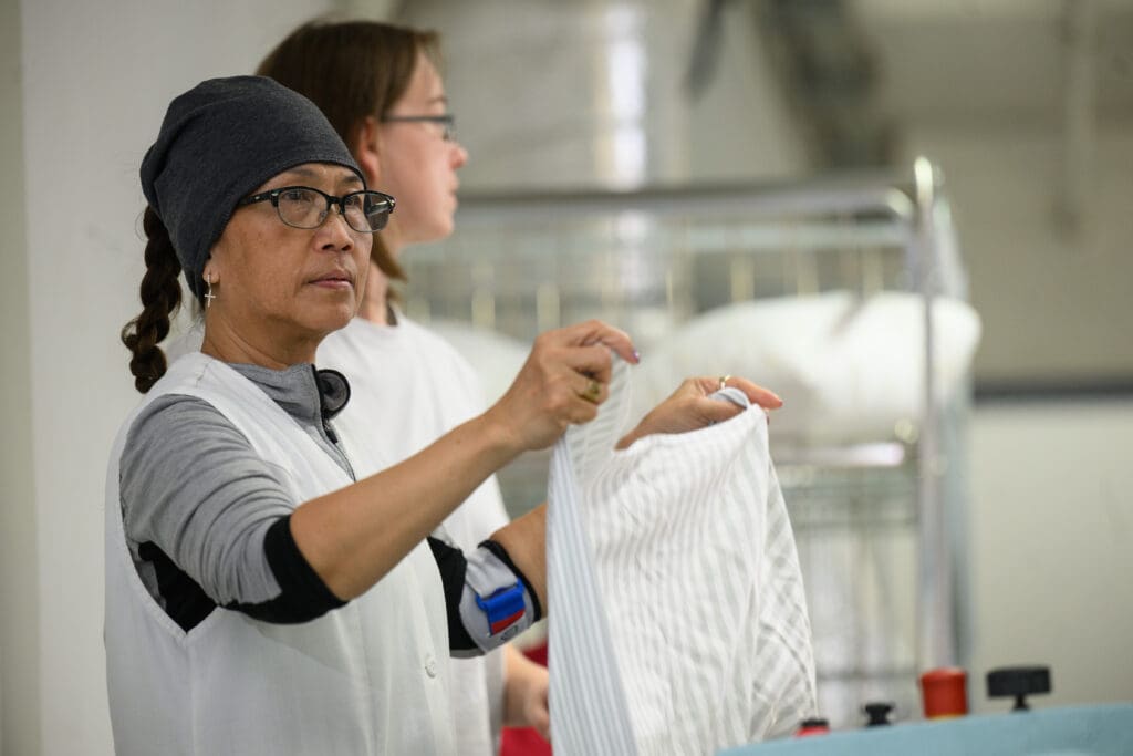 Eine Mitarbeiterin der Vinzenz Wäscherei beim Falten eines Textilstücks