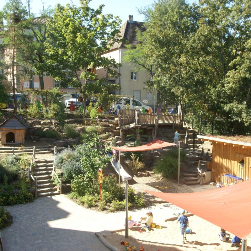 Spielplatz mit Holzbrücke, Holzweg und Holzhäuschen.