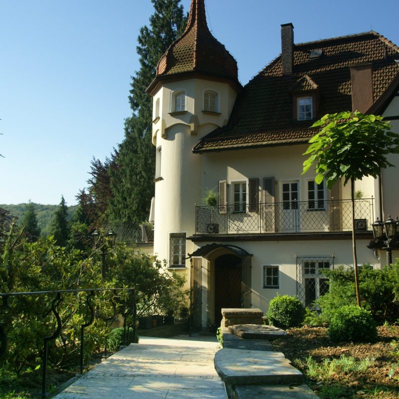 Fußweg aus großen und kleinen Pflastersteinen vor Villa.